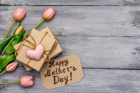 Greetings card for Happy Mothers Day. Gentle pink tulips, handmade felt heart, zero waste packaging gift. Wooden boards backgroundの写真素材