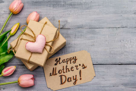 Greetings card for Happy Mothers Day. Gentle pink tulips, handmade felt heart, zero waste packaging gift. Wooden boards backgroundの写真素材