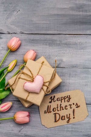 Greetings card for Happy Mothers Day. Gentle pink tulips, handmade felt heart, zero waste packaging gift. Wooden boards backgroundの写真素材