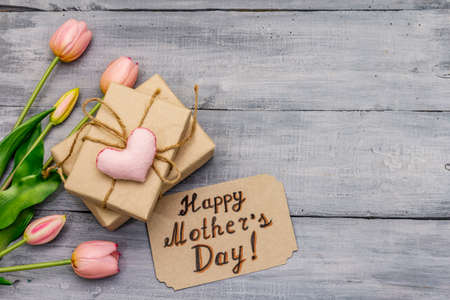 Greetings card for Happy Mothers Day. Gentle pink tulips, handmade felt heart, zero waste packaging gift. Wooden boards backgroundの写真素材