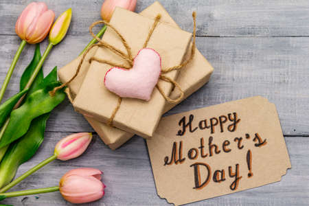Greetings card for Happy Mothers Day. Gentle pink tulips, handmade felt heart, zero waste packaging gift. Wooden boards backgroundの写真素材