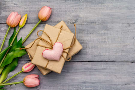 Greetings card, wallpaper, backdrop. Happy Mothers Day, St.Valentines or Wedding. Gentle pink tulips, handmade felt heart, zero waste packaging gift. Wooden boards backgroundの写真素材