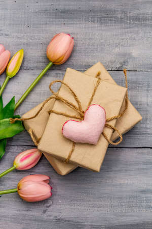 Greetings card, wallpaper, backdrop. Happy Mothers Day, St.Valentines or Wedding. Gentle pink tulips, handmade felt heart, zero waste packaging gift. Wooden boards backgroundの写真素材