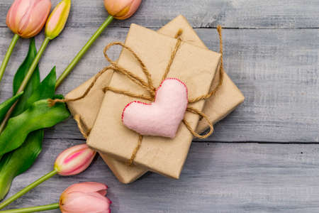 Greetings card, wallpaper, backdrop. Happy Mothers Day, St.Valentines or Wedding. Gentle pink tulips, handmade felt heart, zero waste packaging gift. Wooden boards backgroundの写真素材