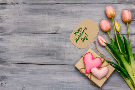 Greetings card for Happy Mothers Day. Gentle pink tulip, handmade felt heart, zero waste packaging gift. Wooden boards backgroundの写真素材