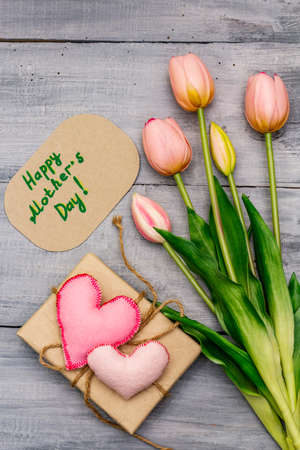 Greetings card for Happy Mothers Day. Gentle pink tulips, handmade felt heart, zero waste packaging gift. Wooden boards backgroundの写真素材