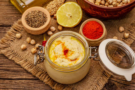 Hummus on old wooden boards background. Dry chickpea, olive oil, lemon, cumin and chili pepper. Traditional food in Middle Eastern and Mediterranean cuisine, top viewの写真素材