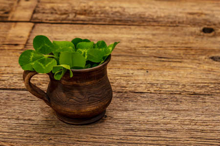 Fresh clover bouquet in ceramic cup. Good luck symbol, St.Patrick's Day concept. Old wooden boards backgroundの写真素材