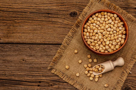 Dry chickpea in ceramic bowl on old wooden boards background. Traditional ingredient for cooking hummus. Middle Eastern and Mediterranean cuisineの写真素材