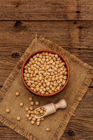 Dry chickpea in ceramic bowl on old wooden boards background. Traditional ingredient for cooking hummus. Middle Eastern and Mediterranean cuisineの写真素材