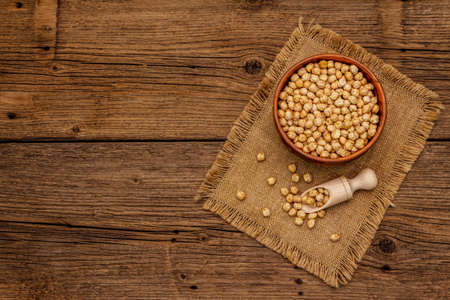 Dry chickpea in ceramic bowl on old wooden boards background. Traditional ingredient for cooking hummus. Middle Eastern and Mediterranean cuisineの写真素材
