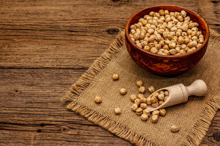 Dry chickpea in ceramic bowl on old wooden boards background. Traditional ingredient for cooking hummus. Middle Eastern and Mediterranean cuisineの写真素材