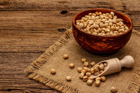 Dry chickpea in ceramic bowl on old wooden boards background. Traditional ingredient for cooking hummus. Middle Eastern and Mediterranean cuisineの写真素材