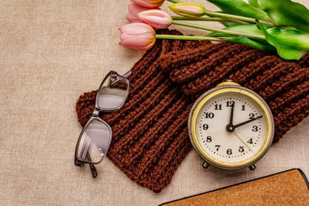 Happy Grandparents Day. Bouquet of gentle rosy tulip, warm knitted scarf, glasses and alarm clock, copy spaceの写真素材