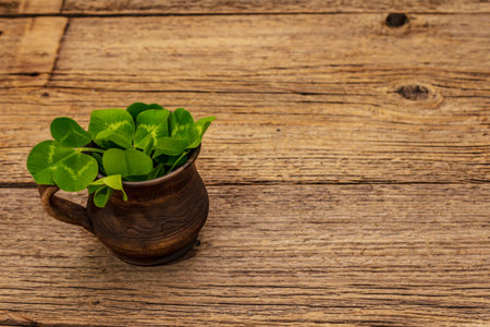 Fresh clover bouquet in ceramic cup. Good luck symbol, St.Patrick's Day concept. Old wooden boards...