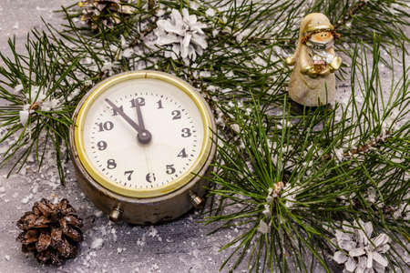 Few minutes to midnight. New Year concept. Alarm clock, pine branch, Christmas decorations. Grey stone concrete backgroundの写真素材