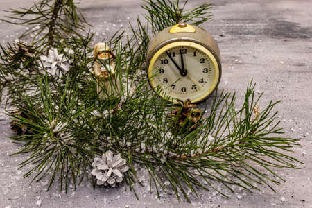 Few minutes to midnight. New Year concept. Alarm clock, pine branch, Christmas decorations. Grey stone concrete backgroundの写真素材