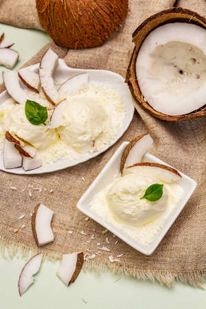 Lactose free coconut ice cream. Special spoon, halves of fruit, flakes. Vegan dessert concept. Light green backgroundの写真素材