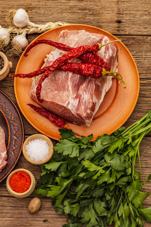 Assorted raw pork meat. Fresh loin, spices, fragrant vegetables and parsley. Vintage wooden boards table, close upの写真素材