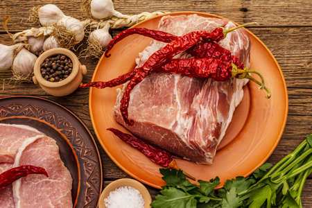 Assorted raw pork meat. Fresh loin, spices, fragrant vegetables and parsley. Vintage wooden boards table, close upの写真素材