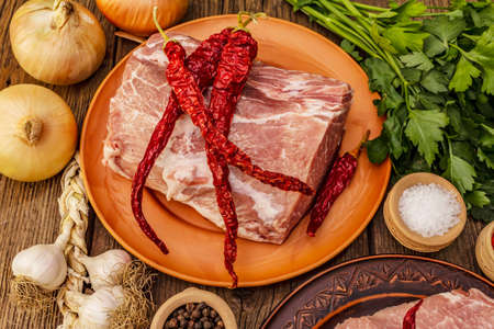Assorted raw pork meat. Fresh loin, spices, fragrant vegetables and parsley. Vintage wooden boards table, close upの写真素材