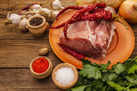 Raw pork meat. Fresh loin, spices, fragrant vegetables and parsley. Vintage wooden boards table, copy spaceの写真素材