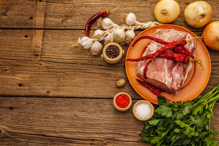 Raw pork meat. Fresh loin, spices, fragrant vegetables and parsley. Vintage wooden boards table, top viewの写真素材
