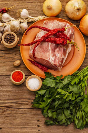 Raw pork meat. Fresh loin, spices, fragrant vegetables and parsley. Vintage wooden boards table, top viewの写真素材