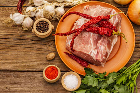 Raw pork meat. Fresh loin, spices, fragrant vegetables and parsley. Vintage wooden boards table, top viewの写真素材