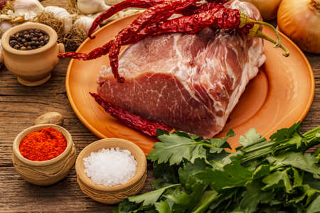 Raw pork meat. Fresh loin, spices, fragrant vegetables and parsley. Vintage wooden boards table, close upの写真素材