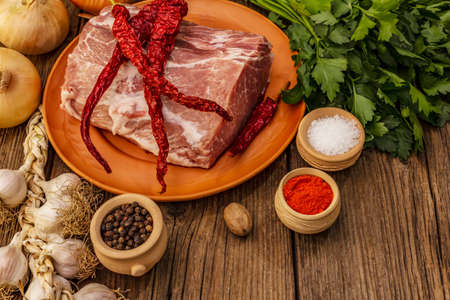 Raw pork meat. Fresh loin, spices, fragrant vegetables and parsley. Vintage wooden boards table, copy spaceの写真素材