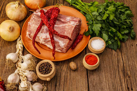 Raw pork meat. Fresh loin, spices, fragrant vegetables and parsley. Vintage wooden boards table, copy spaceの写真素材
