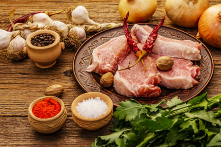 Raw pork meat. Fresh loin, spices, fragrant vegetables and parsley. Vintage wooden boards table, close upの写真素材
