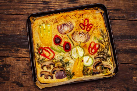 Colorful Garden Focaccia. Fresh ripe vegetables, olive oil, greens. Traditional Italian bakery. Old wooden boards backgroundの写真素材