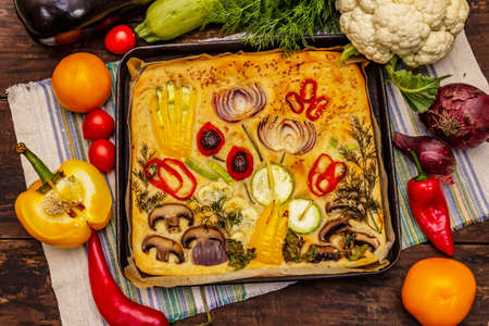 Colorful Garden Focaccia. Fresh ripe vegetables, olive oil, greens. Traditional Italian bakery. Old wooden boards backgroundの写真素材