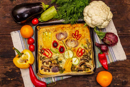 Colorful Garden Focaccia. Fresh ripe vegetables, olive oil, greens. Traditional Italian bakery. Old wooden boards backgroundの写真素材