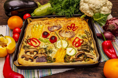 Colorful Garden Focaccia. Fresh ripe vegetables, olive oil, greens. Traditional Italian bakery. Old wooden boards backgroundの写真素材