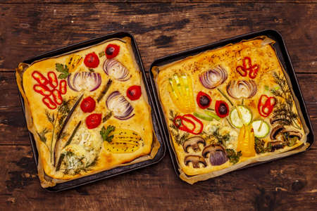 Colorful Garden Focaccia. Fresh ripe vegetables, olive oil, greens. Traditional Italian bakery. Old wooden boards backgroundの写真素材