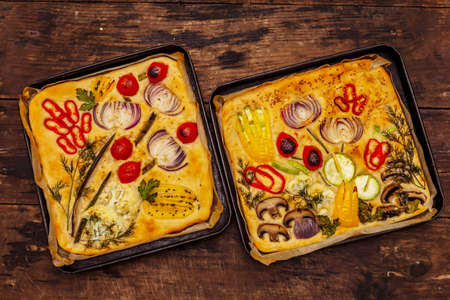 Colorful Garden Focaccia. Fresh ripe vegetables, olive oil, greens. Traditional Italian bakery. Old wooden boards backgroundの写真素材