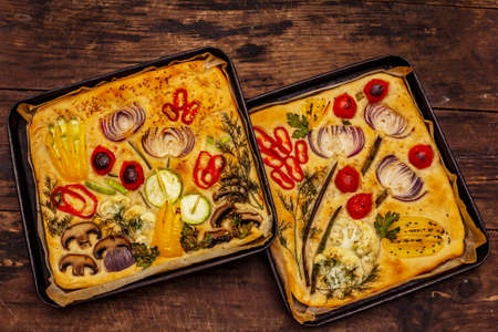 Colorful Garden Focaccia. Fresh ripe vegetables, olive oil, greens. Traditional Italian bakery. Old wooden boards backgroundの写真素材