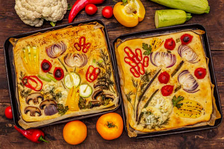 Colorful Garden Focaccia. Fresh ripe vegetables, olive oil, greens. Traditional Italian bakery. Old wooden boards backgroundの写真素材