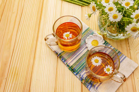 Chamomile tea. Fresh flowers, summer hot drink concept. Alternative medicine, lifestyle.Wooden boards background, copy spaceの写真素材