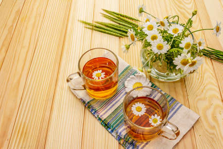Chamomile tea. Fresh flowers, summer hot drink concept. Alternative medicine, lifestyle.Wooden boards background, copy spaceの写真素材