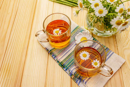 Chamomile tea. Fresh flowers, summer hot drink concept. Alternative medicine, lifestyle.Wooden boards background, copy spaceの写真素材