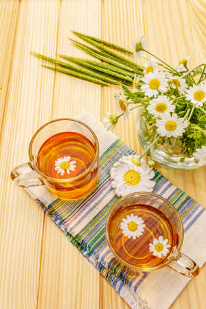 Chamomile tea. Fresh flowers, summer hot drink concept. Alternative medicine, lifestyle.Wooden boards background, top viewの写真素材