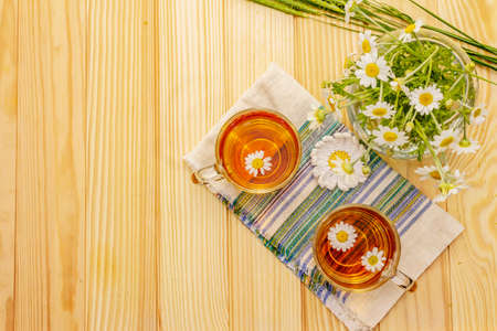 Chamomile tea. Fresh flowers, summer hot drink concept. Alternative medicine, lifestyle.Wooden boards background, top viewの写真素材