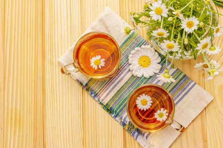 Chamomile tea. Fresh flowers, summer hot drink concept. Alternative medicine, lifestyle.Wooden boards background, top viewの写真素材