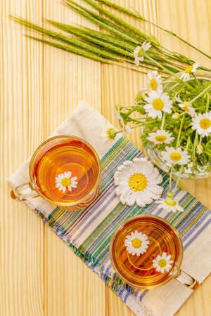 Chamomile tea. Fresh flowers, summer hot drink concept. Alternative medicine, lifestyle.Wooden boards background, top viewの写真素材