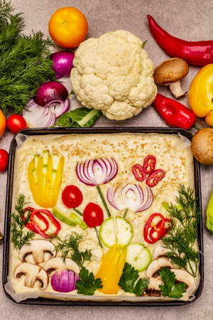 Raw Garden Focaccia. Fresh dough and vegetables, olive oil, greens. Colorful gardenscape, stone concrete backgroundの写真素材