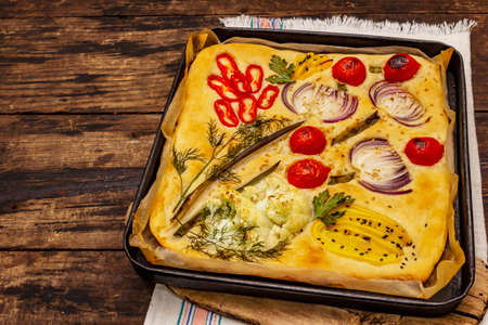 Colorful Garden Focaccia. Fresh ripe vegetables, olive oil, greens. Traditional Italian bakery. Old wooden boards backgroundの写真素材